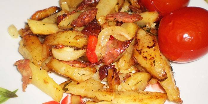 Pommes de terre frites avec des saucisses et des oignons dans une casserole