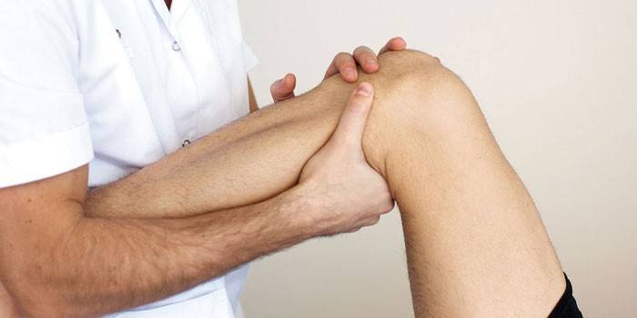 O médico examina o joelho do paciente