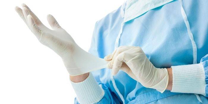 Der Arzt zieht einen Handschuh an