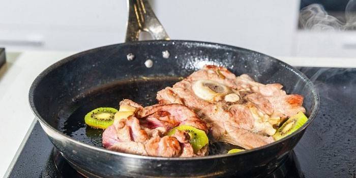 Fried meat with kiwi in a pan