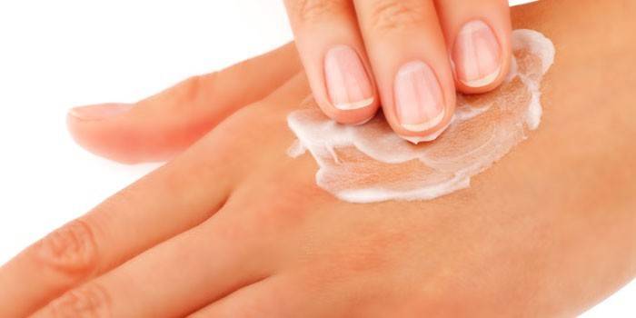 Mulher coloca creme nas mãos dela