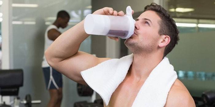 Mann in der Turnhalle trinkt einen Proteindrink.
