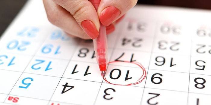 La fille trace la date de l'ovulation sur le calendrier