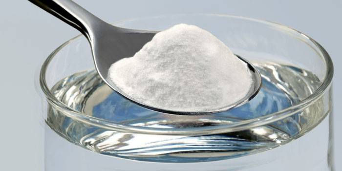 Un bicchiere d'acqua e un cucchiaino di soda