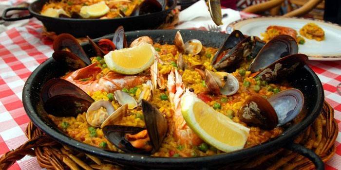 Paella pronta con frutti di mare e limone in padella