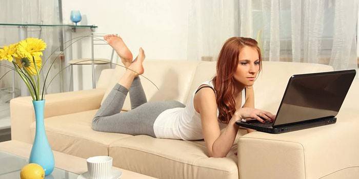 La ragazza si trova su un divano con un computer portatile