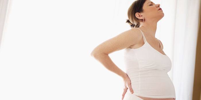 Người phụ nữ mang thai giữ hai tay trên lưng dưới