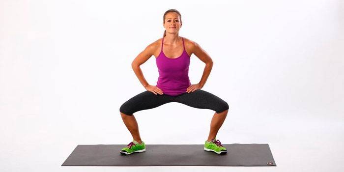 Fille effectue des squats plie