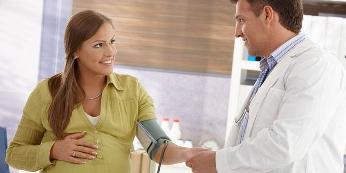 Un médico mide la presión de una mujer embarazada.