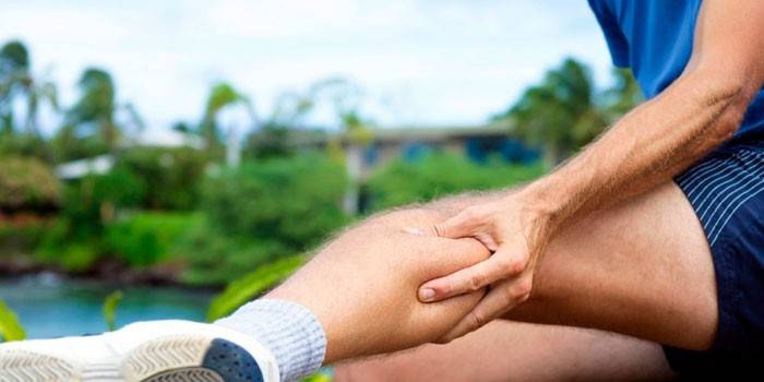 Mann hält seinen Wadenmuskel in der Hand
