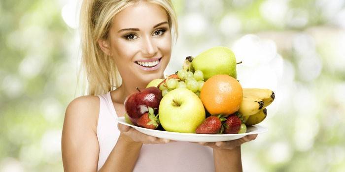 Fille tient un plat avec des fruits et des baies.