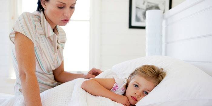 Người phụ nữ đang ngồi trên giường gần em bé.