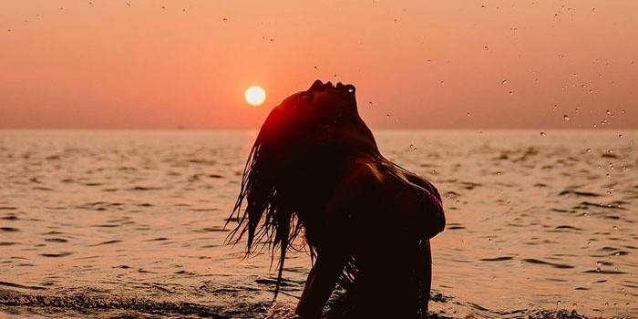 Κορίτσι στη θάλασσα στο φόντο της αυγής