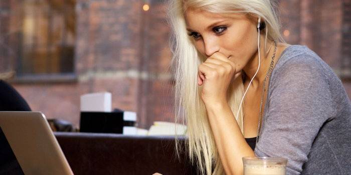 Menina sentada em um laptop em fones de ouvido