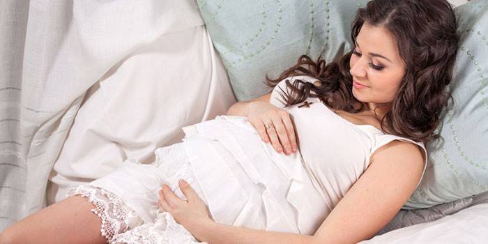 Fille enceinte se trouve sur des oreillers