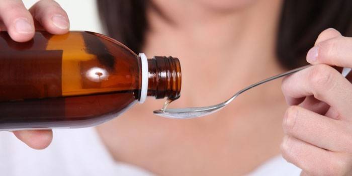 La ragazza versa lo sciroppo in un cucchiaio
