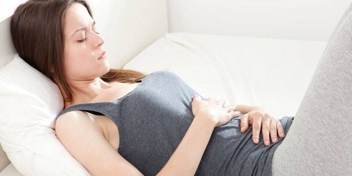 A menina encontra-se na cama e mantém as mãos na barriga