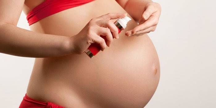 Fille enceinte avec de la crème dans ses mains
