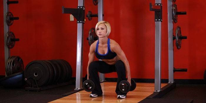 Kız dumbbells ile crouches.