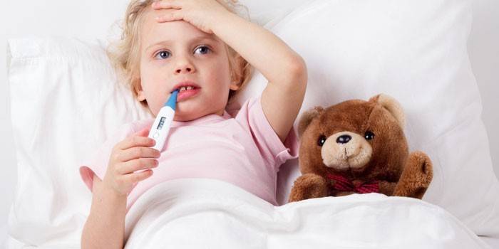 Bambino a letto con un termometro in bocca