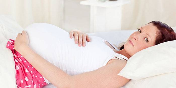Schwangere Frau im Bett liegend