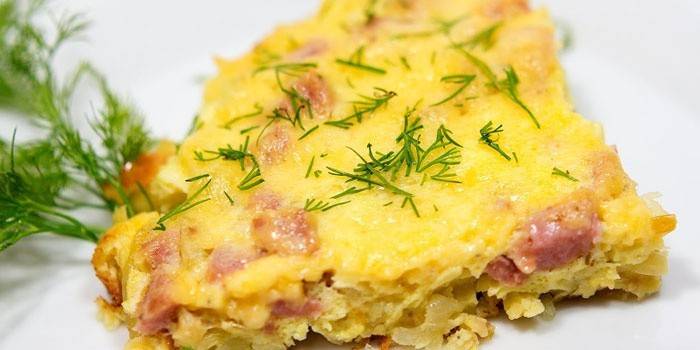 O bucată de omletă cu cârnați sub un capac de brânză
