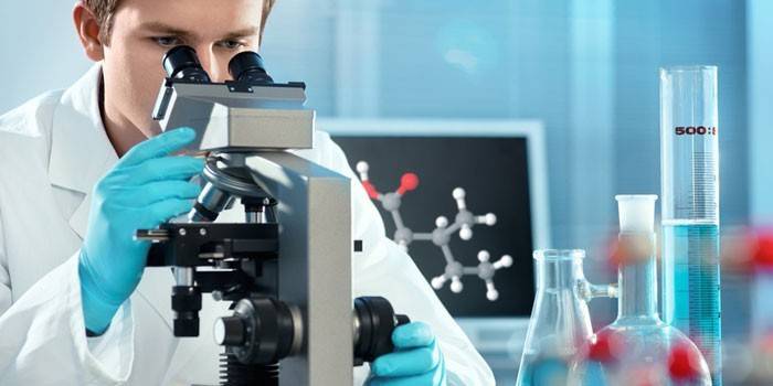 Lab tehniķis, kurš skatās caur mikroskopu