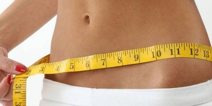 Das Mädchen misst das Volumen der Hüften mit einem Zentimeter