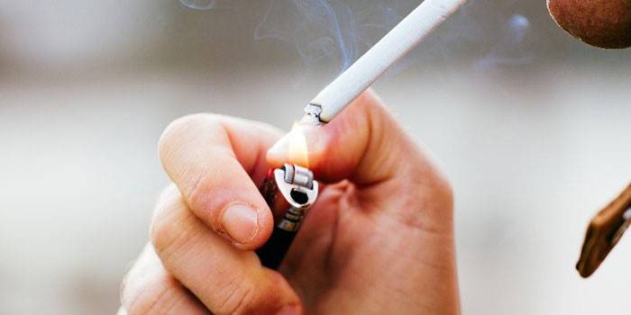Muž zapaľuje cigaretu zo zapaľovača