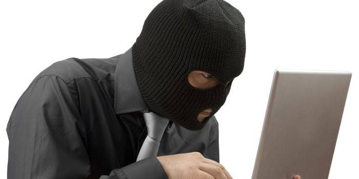 Mies balaclava kannettavan kanssa