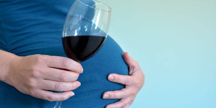 Fata însărcinată cu un pahar de vin
