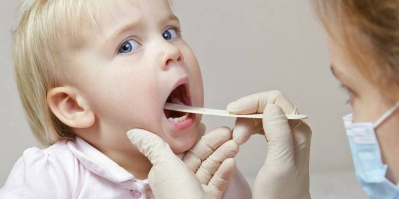 El doctor mira la garganta de un niño.