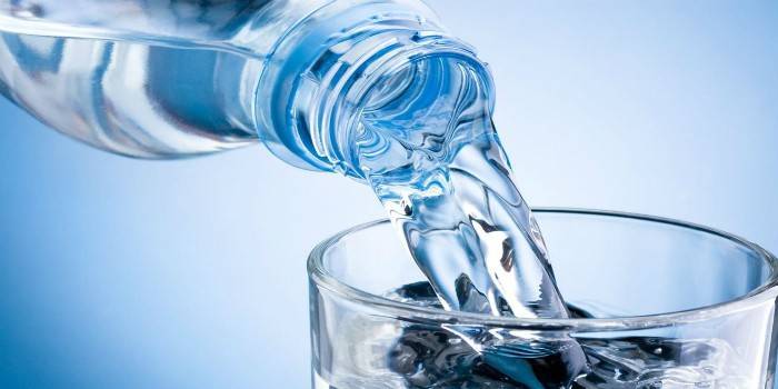 L'acqua di una bottiglia viene versata in un bicchiere