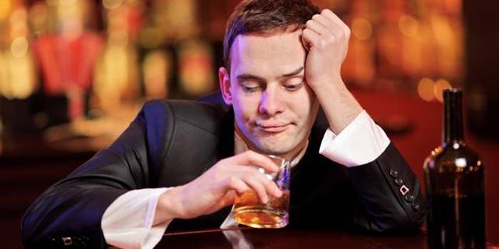 Az ember tartja a kezében egy pohár alkoholt