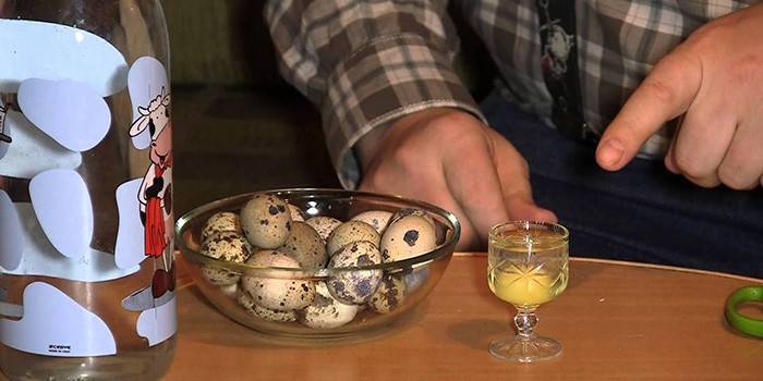 Homme, œufs de caille dans un bol en verre et un œuf cru dans un verre
