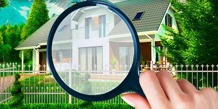 Sinusuri ng tao ang isang bahay sa pamamagitan ng isang magnifier