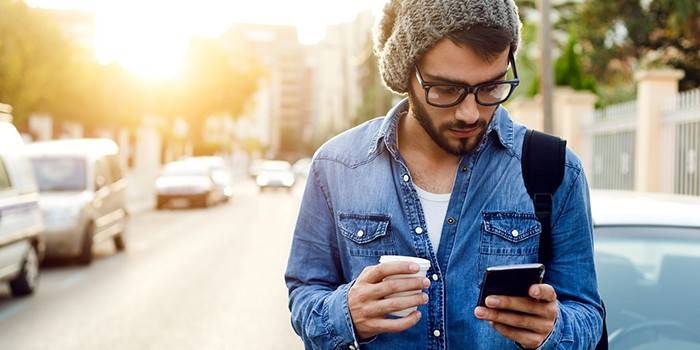 Facet z kawą i smartphone w ręce