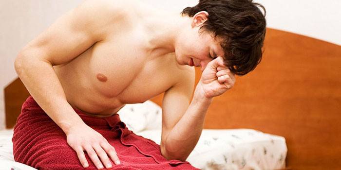 Un uomo in un asciugamano si siede su un letto