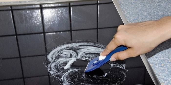 Usando um raspador para limpar a superfície vitrocerâmica