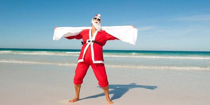 Um homem em uma fantasia de Papai Noel na praia