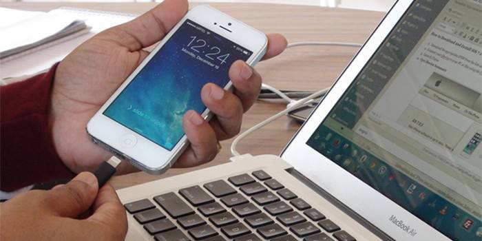 رجل يربط جهاز iPhone بجهاز كمبيوتر محمول عبر الكابل