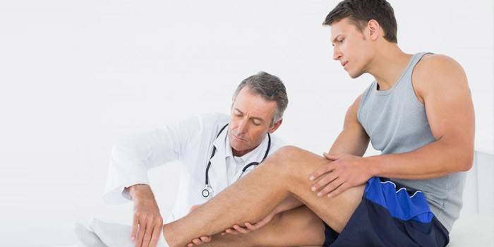 El médico examina la pierna del paciente.