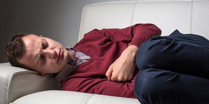 Một người đàn ông nằm và giữ tay trên bụng