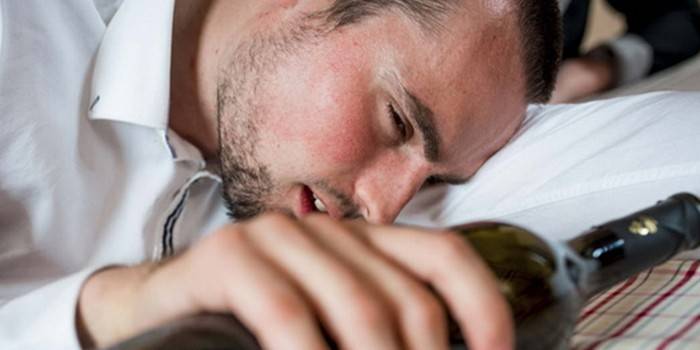 Hombre durmiendo con una botella en la mano
