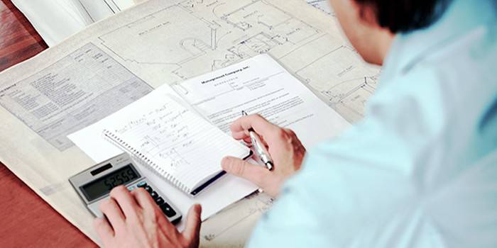 Um homem faz cálculos com uma calculadora