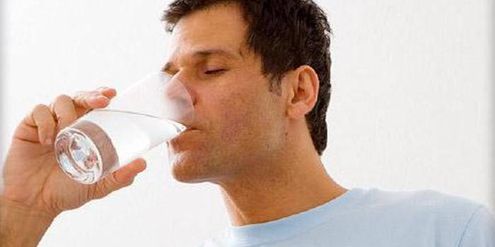 Човек пије воду из чаше