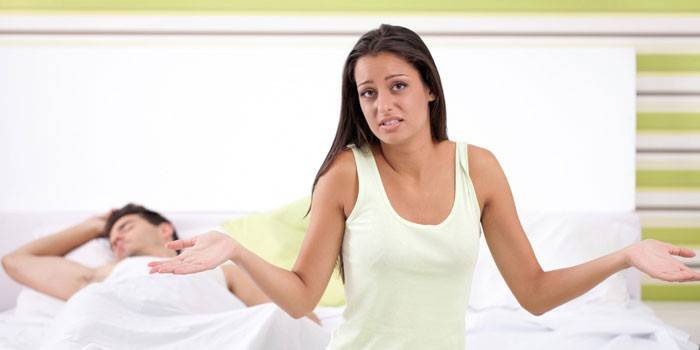 Mujer frustrada y chico dormido en la cama.