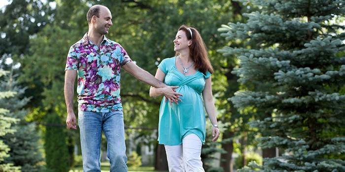 Nėščia moteris su vyru pasivaikščioti po parką