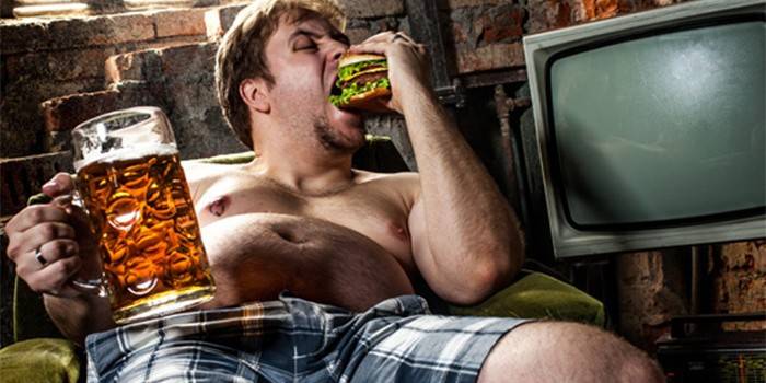 Fleisch fressend ein Hamburger und ein Glas Bier anhalten
