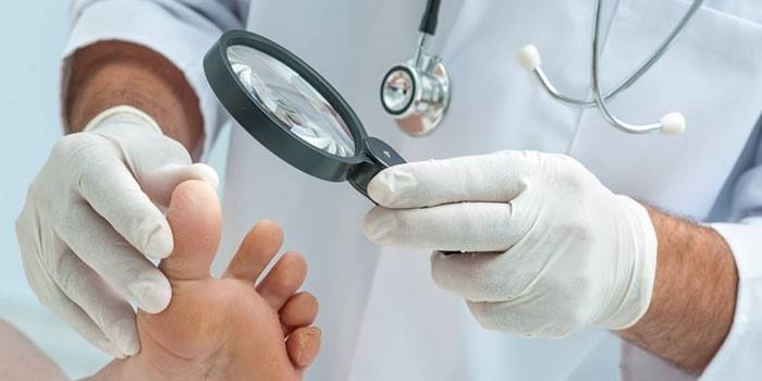 O médico examina a perna do paciente através de uma lupa